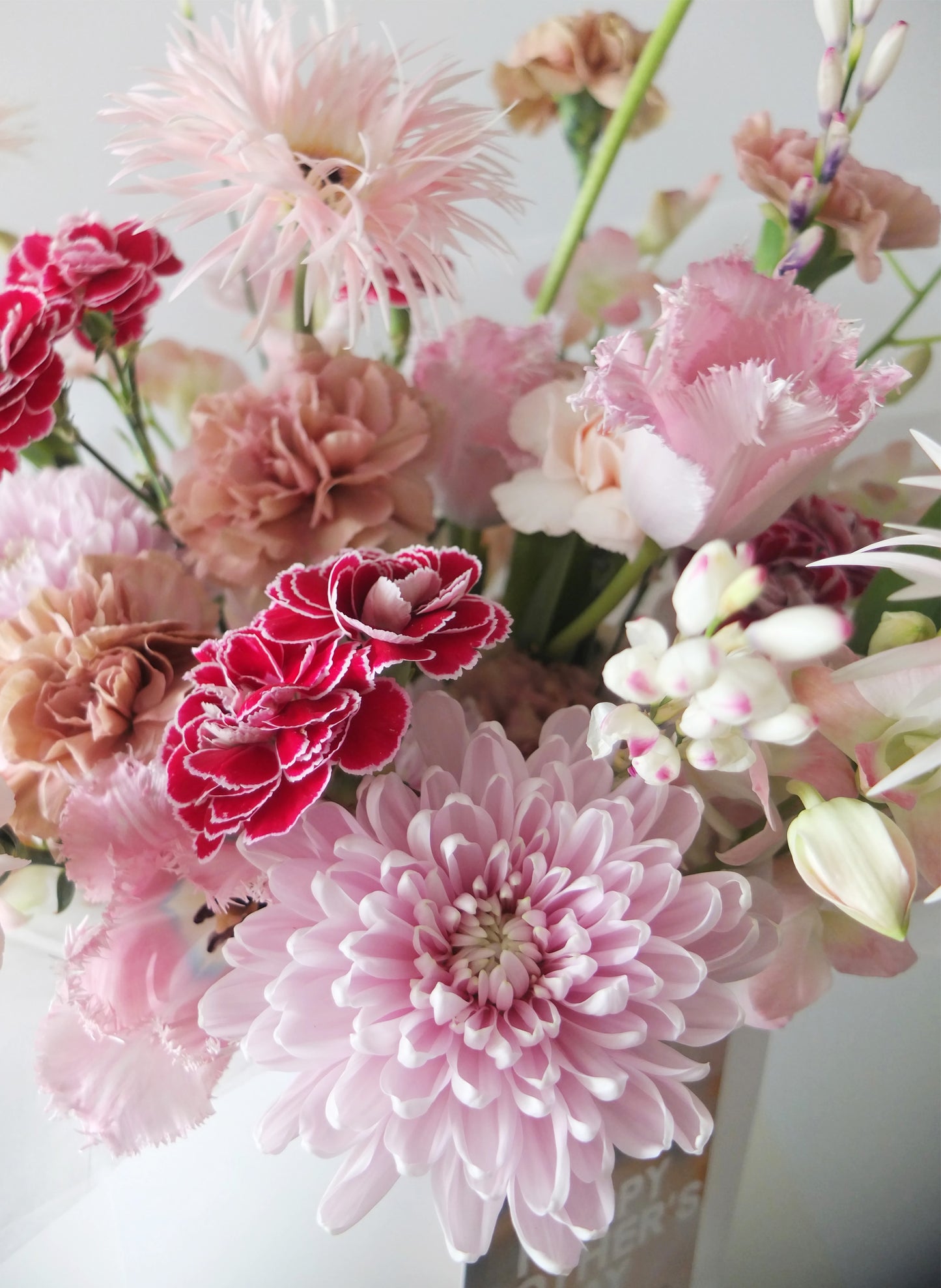 淡粉色菊花、太陽菊、鬱金香與紅色康乃馨組成的母親節花束，層次分明。